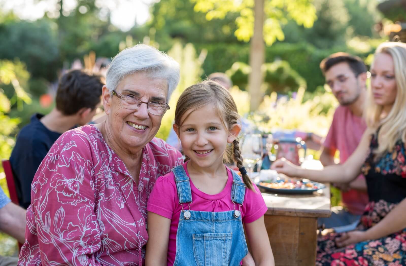 An older adult woman having lunch with her family outdoors.