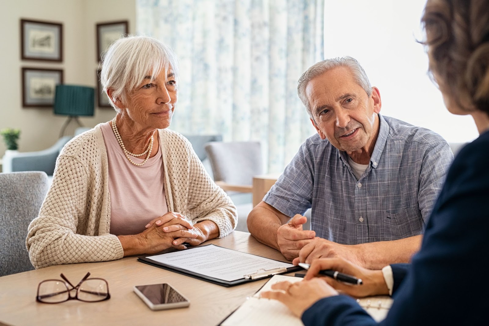 An older adult couple discussing financial assistance options with a financial advisor.