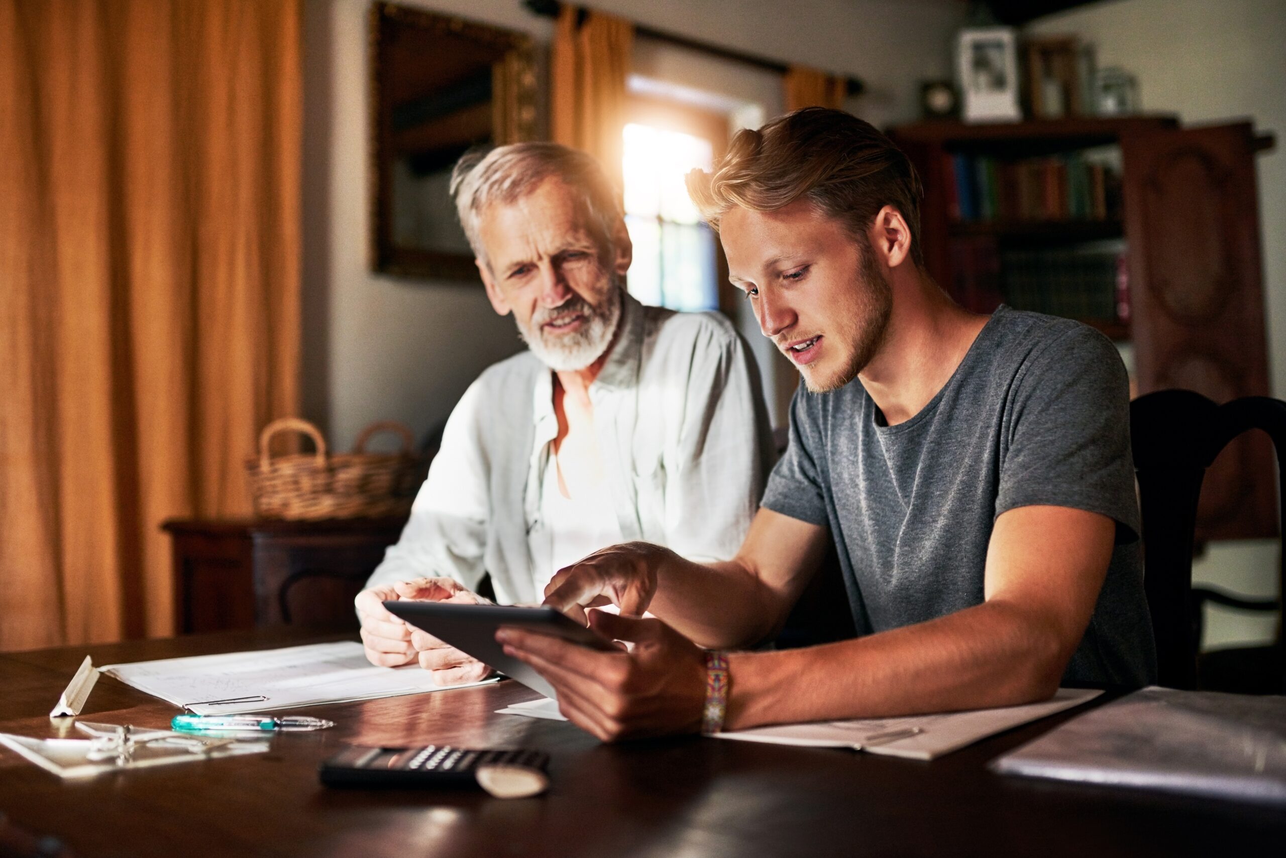 An adult son helps his older adult father organize finances for his move into a senior living home.