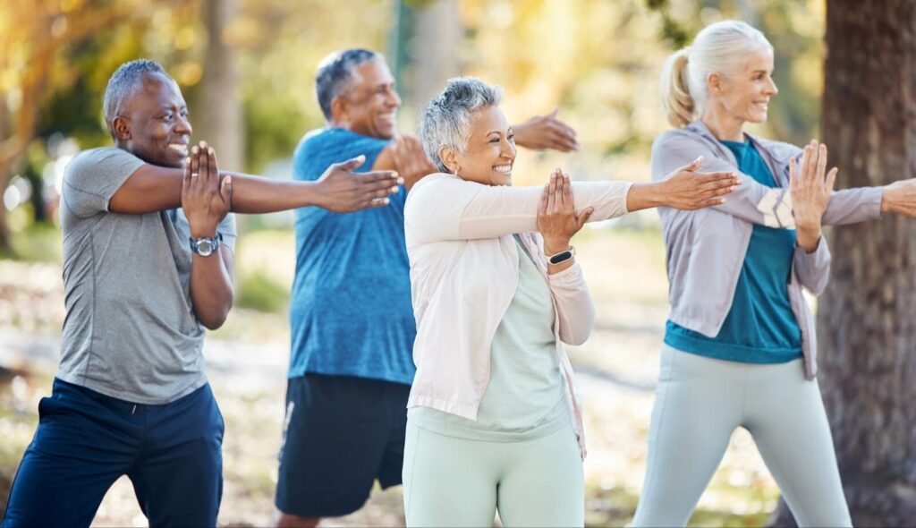 A group of older adults stretching together in the outdoors.