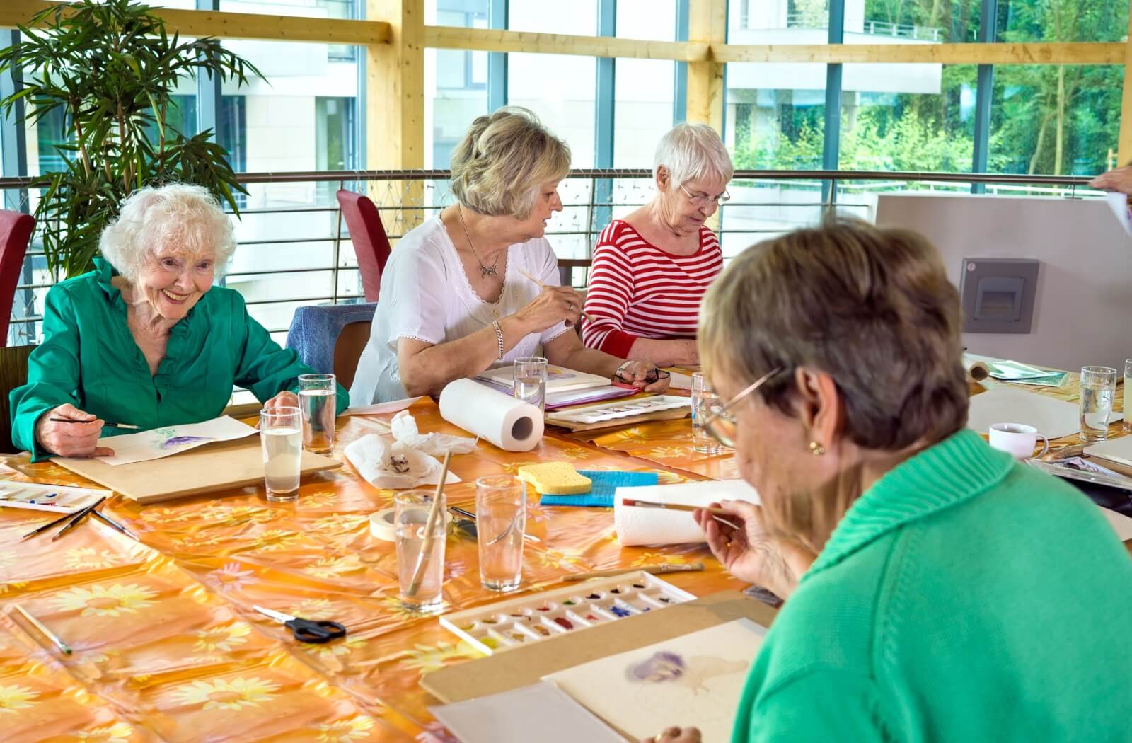 A group of older adults taking a painting class and socializing in memory care.