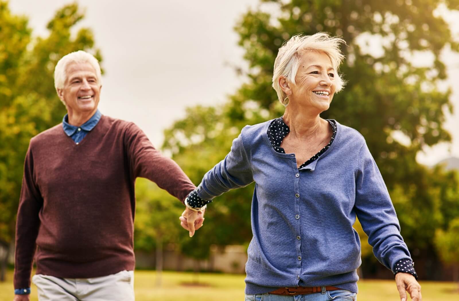 Happy older couple holding hands and enjoying a sunny day outdoors, embracing connection and living life to the fullest.