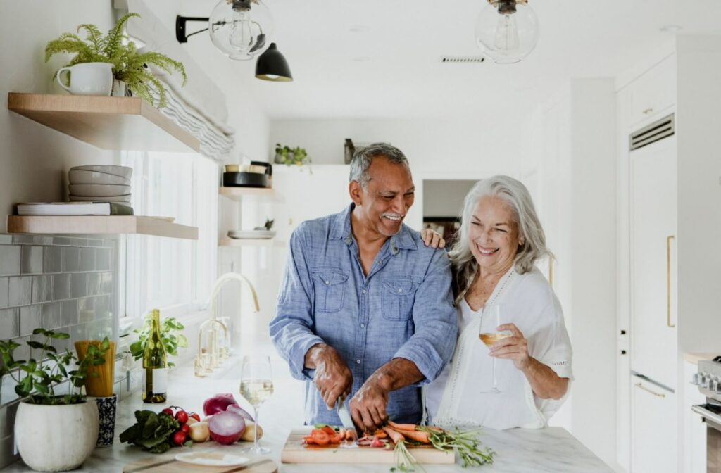 Smiling older couple cooking together in a bright kitchen, sharing a moment of connection.